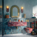 Bathroom setting featuring Foundry Bricks Marine Blue 6.5x20cm wall tiles, showcasing rich blue tones with subtle tonal variation, installed in a vertical layout across the walls, paired with terrazzo effect floor tiles, a statement red marble basin and brass fittings for a bold, design-led contrast.