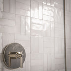 Bathroom interior featuring Foundry Bricks Chalk White 6.5x20cm wall tiles, laid in a structured patterned layout across shower walls, paired with marble effect floor tiles and a green marble vanity for a refined, design-led finish.