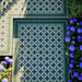 Greenbrook Manor corner 20cm x 20cm porcelain tiles forming a classic Victorian-style green, black and white geometric border around a patterned tiled area, set outdoors beside planting and flowers.