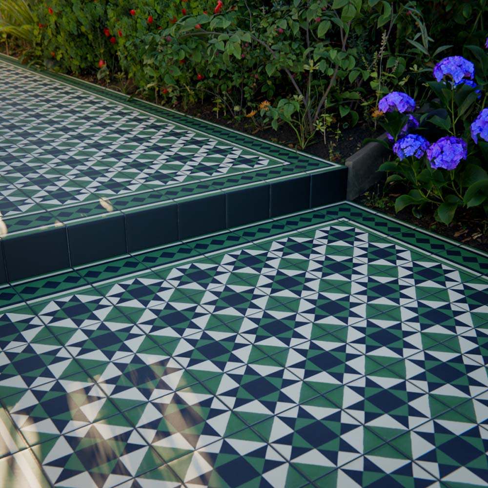 Outdoor garden steps finished with Greenbrook Manor anti-slip encaustic Victorian-style porcelain tiles, featuring a classic green, black and white geometric pattern with coordinating border tiles and planting along the edges.