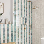 Bathroom interior featuring Saigon Celadon Green and Saigon White 10x10cm Moroccan-style square wall tiles installed in a vertical striped shower design, styled with brushed brass fittings, built-in niche, and a light, spa-inspired setting.
