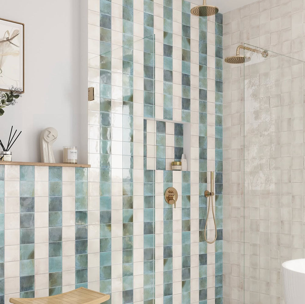 Bathroom interior featuring Saigon Celadon Green and Saigon White 10x10cm Moroccan-style square wall tiles installed in a vertical striped shower design, styled with brushed brass fittings, built-in niche, and a light, spa-inspired setting.
