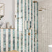 Bathroom interior featuring Saigon Celadon Green and Saigon White 10x10cm Moroccan-style square wall tiles installed in a vertical striped shower design, styled with brushed brass fittings, built-in niche, and a light, spa-inspired setting.