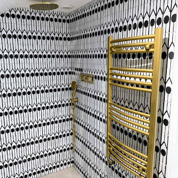 Shower area featuring Almeria Felis Moroccan-style porcelain wall tiles in a bold black and white geometric dot and line pattern, 20x20cm, paired with brass fixtures.