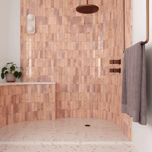 Shower enclosure featuring Saigon Rose Pink Brick Wall tiles in a Moroccan-inspired style, 5.1 × 16.1cm glossy ceramic tiles in soft blush and rose tones, paired with copper shower fittings.