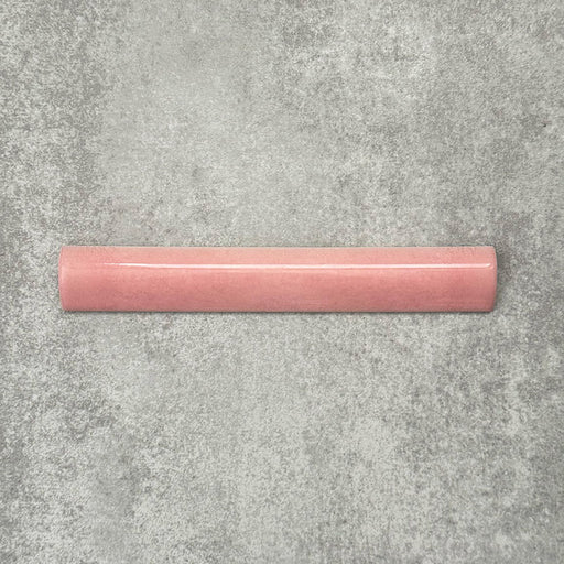 Zellige Rose Pink Bullnose 3 × 20cm Moroccan-style ceramic trim tiles in soft blush and dusty pink tones, shown with a smooth rounded edge and subtle glaze variation, arranged on a textured grey background to highlight the handcrafted zellige-effect finish and decorative edging profile.
