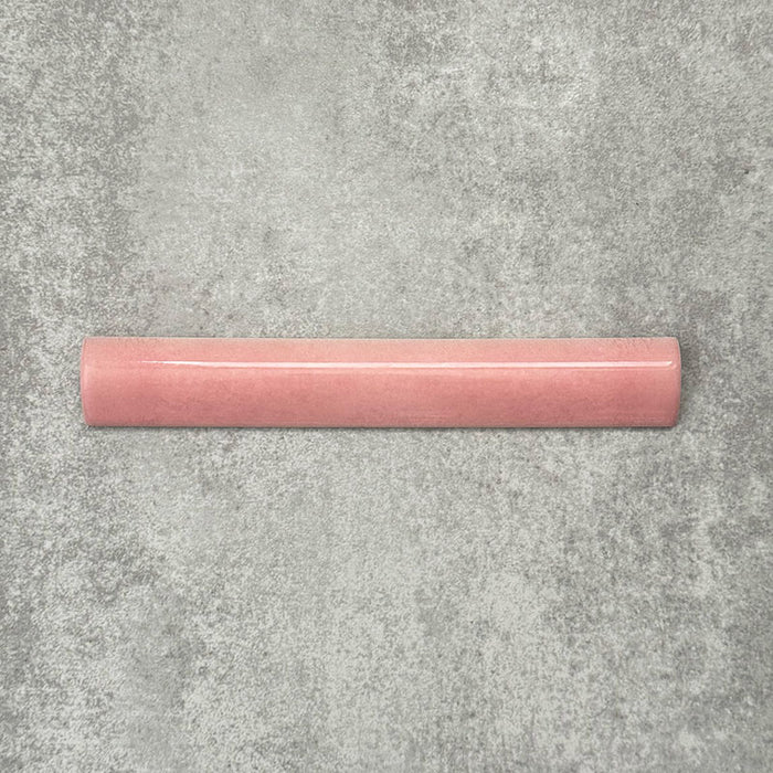 Zellige Rose Pink Bullnose 3 × 20cm Moroccan-style ceramic trim tiles in soft blush and dusty pink tones, shown with a smooth rounded edge and subtle glaze variation, arranged on a textured grey background to highlight the handcrafted zellige-effect finish and decorative edging profile.