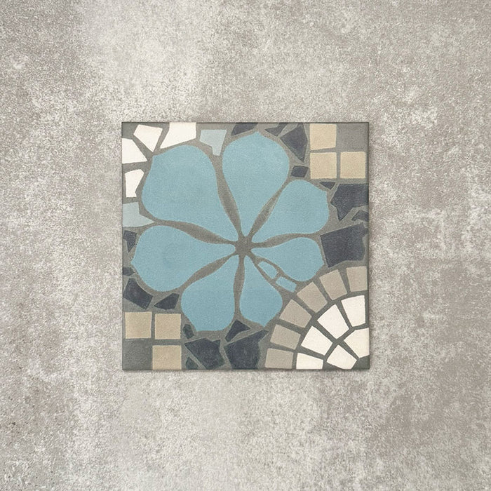 Nantes Azul Blue Moroccan-style tile in a 20x20cm format, shown as a single tile. The design features a soft blue floral motif set against mosaic-style detailing in muted greys, stone tones and white, highlighting the handcrafted, decorative character of this Moroccan-inspired patterned tile.