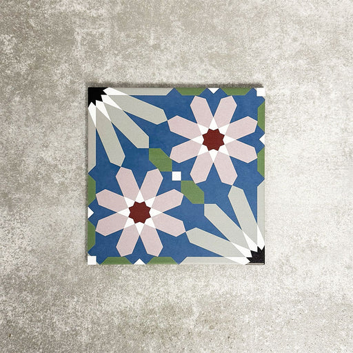 Single Fez Artisan 20x20cm Moroccan-style porcelain tile displayed against a textured grey background, highlighting the multicolour geometric design with soft blue, blush pink, green and terracotta star motifs in an encaustic-inspired pattern.