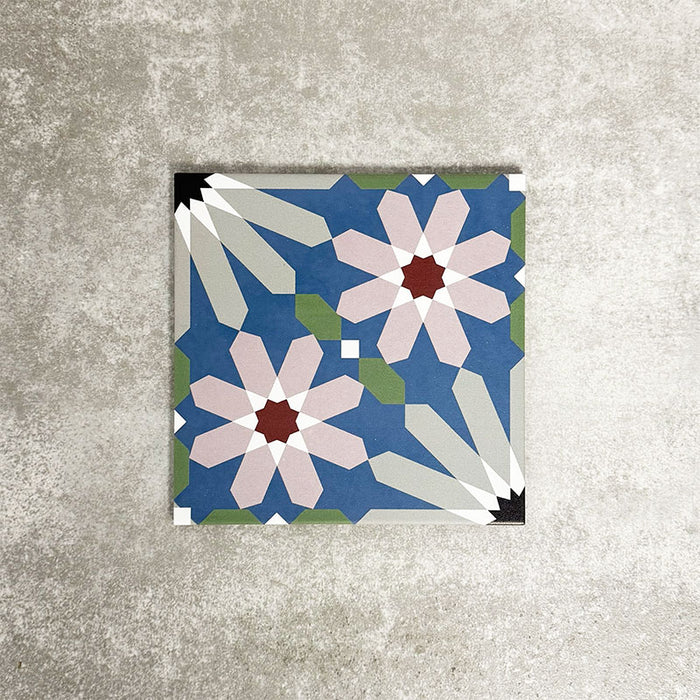 Single Fez Artisan 20x20cm Moroccan-style porcelain tile displayed against a textured grey background, highlighting the multicolour geometric design with soft blue, blush pink, green and terracotta star motifs in an encaustic-inspired pattern.