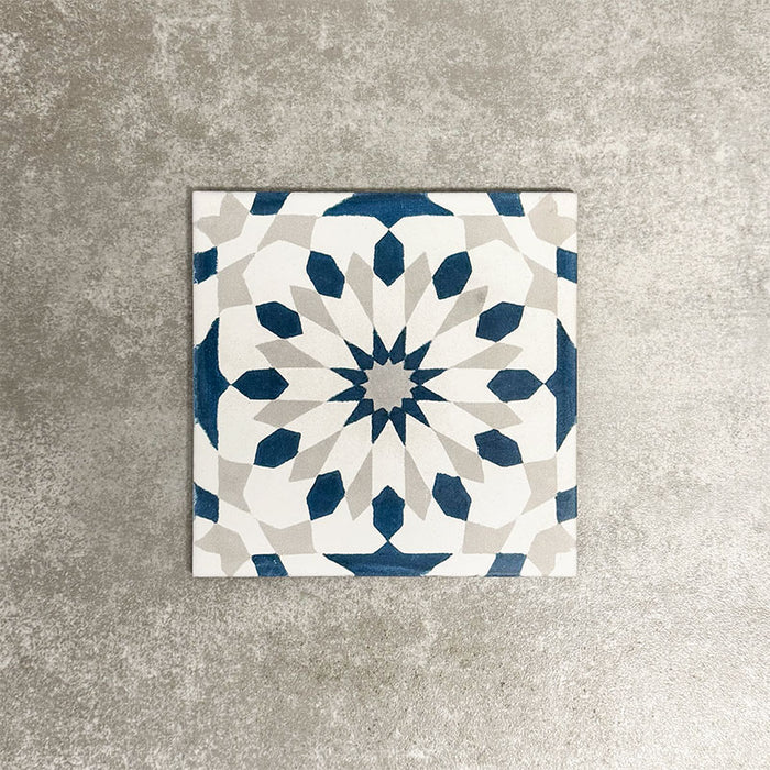 Souk Blue A 20×20cm Moroccan-style porcelain tile with a blue, white and grey geometric pattern.