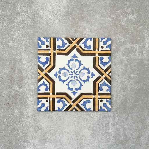 Viscount Maestro 20×20cm Victorian-style porcelain wall and floor tile featuring an ornate geometric and floral motif in blue, white and warm ochre tones, photographed as a single tile on a neutral grey background.