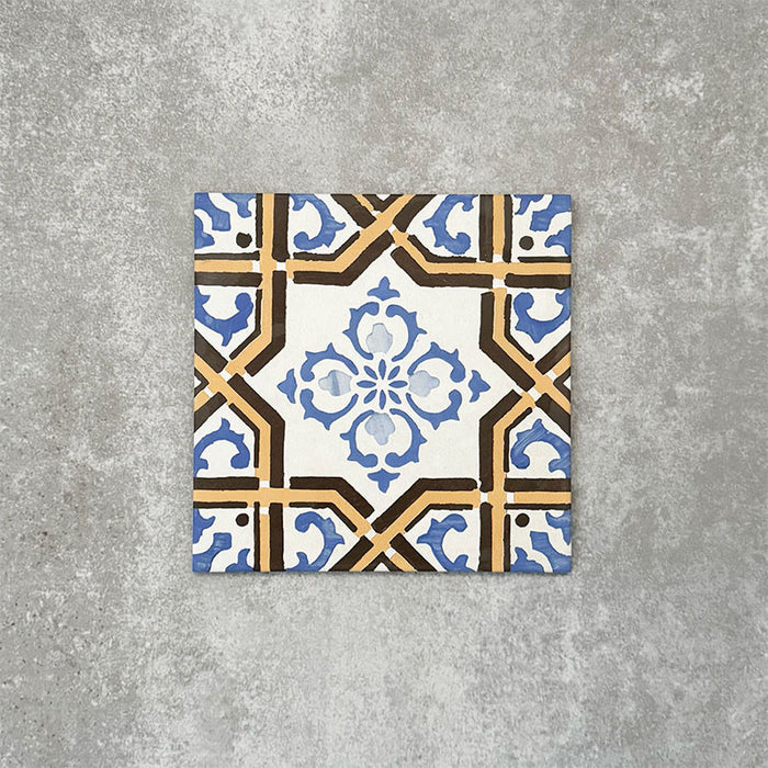 Viscount Maestro 20×20cm Victorian-style porcelain wall and floor tile featuring an ornate geometric and floral motif in blue, white and warm ochre tones, photographed as a single tile on a neutral grey background.