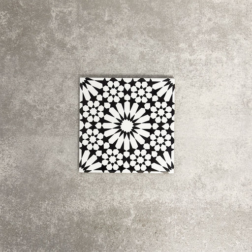 Fez Mini Winter Moroccan-style porcelain tile shown as a single tile, featuring an intricate black and white geometric star pattern inspired by traditional Moroccan design. The 15 × 15cm square format highlights the fine encaustic-effect detailing and strong contrast, making it ideal for creating striking feature walls, splashbacks, or patterned floors in both contemporary and classic interiors.
