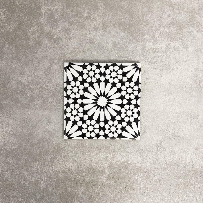Fez Mini Winter Moroccan-style porcelain tile shown as a single tile, featuring an intricate black and white geometric star pattern inspired by traditional Moroccan design. The 15 × 15cm square format highlights the fine encaustic-effect detailing and strong contrast, making it ideal for creating striking feature walls, splashbacks, or patterned floors in both contemporary and classic interiors.