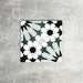 Fez Orchid Moroccan style porcelain tile with a geometric star pattern in soft green, black and white, 20cm x 20cm