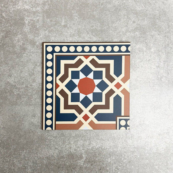 Single Balthazar Grand Corner 20×20cm porcelain tile displayed against a neutral stone-effect background, featuring a Moroccan-inspired geometric corner border design in deep blue, warm brown, terracotta and cream tones, designed to frame patterned layouts with a cohesive, decorative finish.