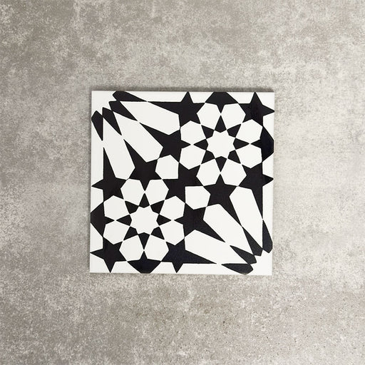Fez Winter Moroccan-style porcelain tile shown as a single tile sample. The 20 × 20cm tile features a bold black and white geometric star pattern inspired by traditional Moroccan designs, with sharp contrast and crisp lines. The encaustic-effect finish highlights the intricate detailing, making it ideal for statement floors, splashbacks or feature walls in both modern and classic interiors.