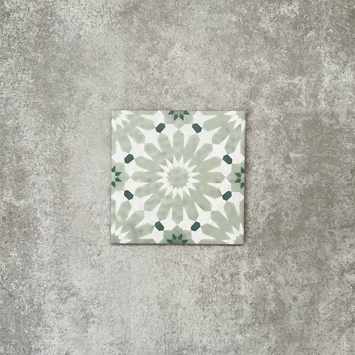 Single Fez Mini Jade Green 15x15cm Moroccan-style porcelain tile displayed against a textured grey background, highlighting the soft jade green and white geometric star pattern with an encaustic-inspired finish.