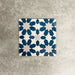 Souk Blue C 20×20cm Moroccan-style porcelain tile with a blue, white and grey geometric pattern.