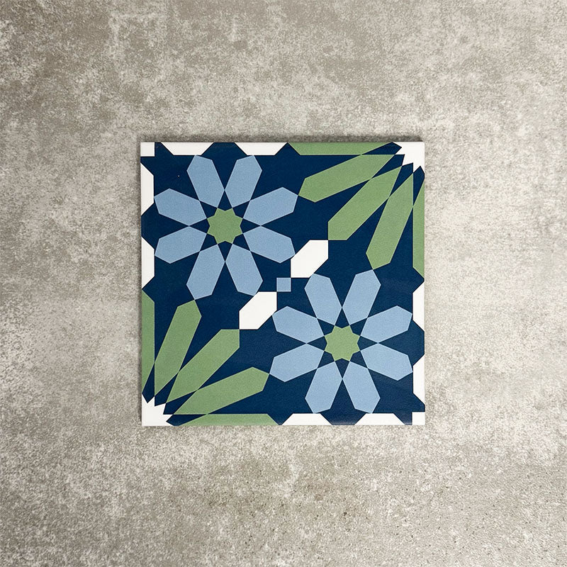 Single Fez Springs 20x20cm Moroccan-style porcelain tile displayed against a textured grey background, highlighting the geometric floral design in layered navy, blue and soft green tones with an encaustic-inspired finish.