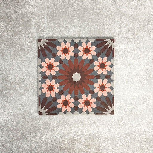 Fez Rosso Moroccan-style porcelain tile shown as a single 20 × 20cm tile, highlighting the intricate geometric pattern in full detail. Deep terracotta and earthy red tones radiate from the centre, layered with soft blush pink star motifs and set against a muted grey background. The balanced, symmetrical design draws inspiration from traditional Moroccan tilework while the porcelain finish keeps it practical and durable. A bold yet elegant choice.