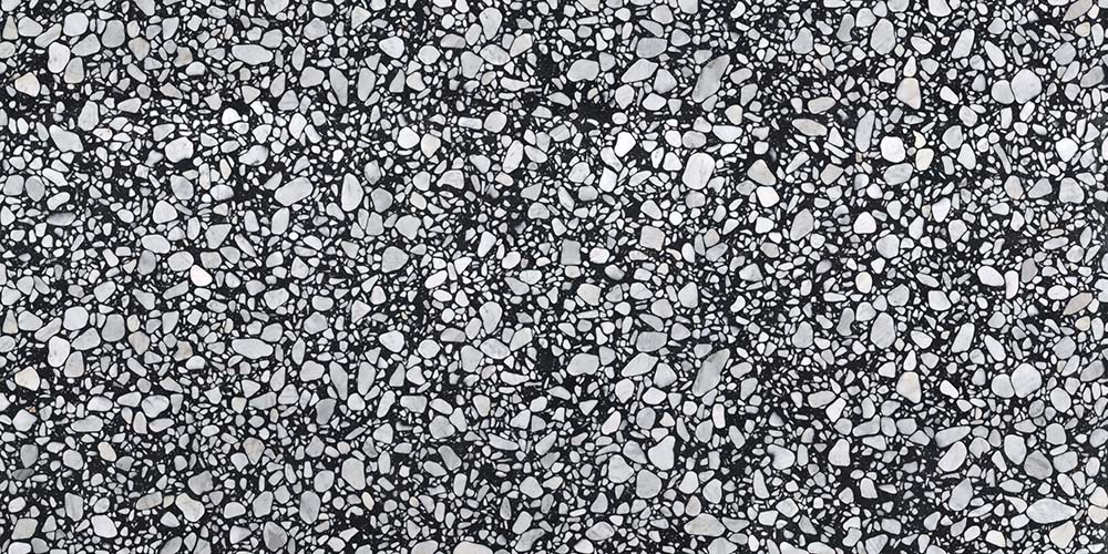 Close-up of Shards Terrazzo Nero 59x118cm matt porcelain wall and floor tile, showcasing a bold black base with varied white aggregate pieces, creating a striking terrazzo effect with natural variation and texture.