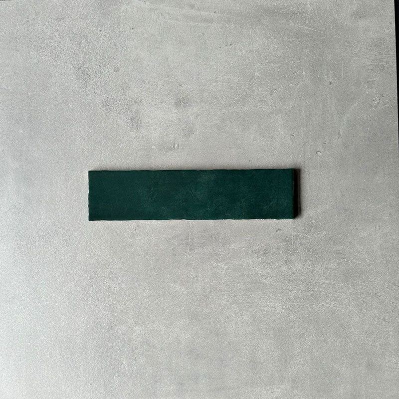 Single Nairobi gloss moss green handmade-effect tile shown close up, highlighting the deep green tone, subtle surface texture and gently uneven edges against a neutral background.