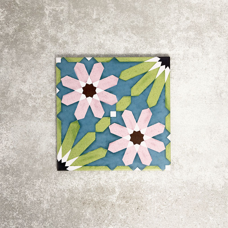 Single Fez Summer 20x20cm Moroccan-style porcelain tile displayed against a textured grey background, highlighting the vibrant geometric floral design in soft green, blue and blush pink tones with an encaustic-inspired finish.