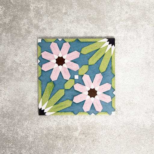Single Fez Summer 20x20cm Moroccan-style porcelain tile displayed against a textured grey background, highlighting the vibrant geometric floral design in soft green, blue and blush pink tones with an encaustic-inspired finish.