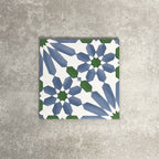 Single Fez Ocean Blue 20x20cm Moroccan-style porcelain tile displayed against a textured grey background, highlighting the blue, white and green geometric star pattern with a traditional encaustic-inspired design.