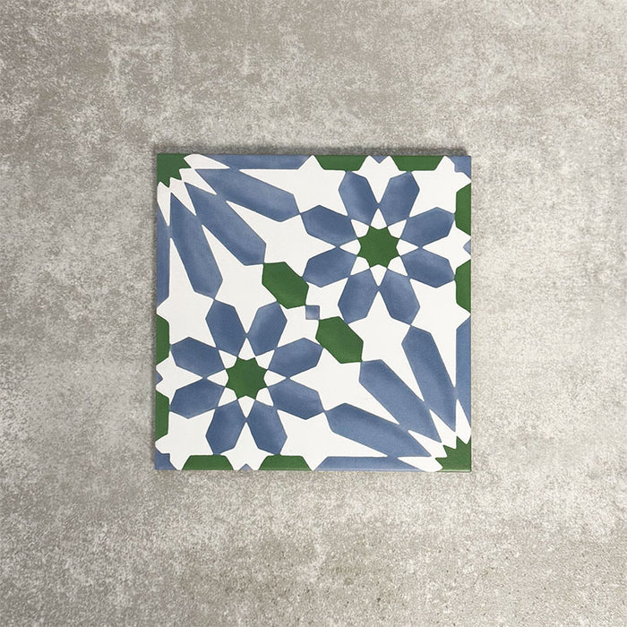 Single Fez Ocean Blue 20x20cm Moroccan-style porcelain tile displayed against a textured grey background, highlighting the blue, white and green geometric star pattern with a traditional encaustic-inspired design.