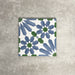 Single Fez Ocean Blue 20x20cm Moroccan-style porcelain tile displayed against a textured grey background, highlighting the blue, white and green geometric star pattern with a traditional encaustic-inspired design.