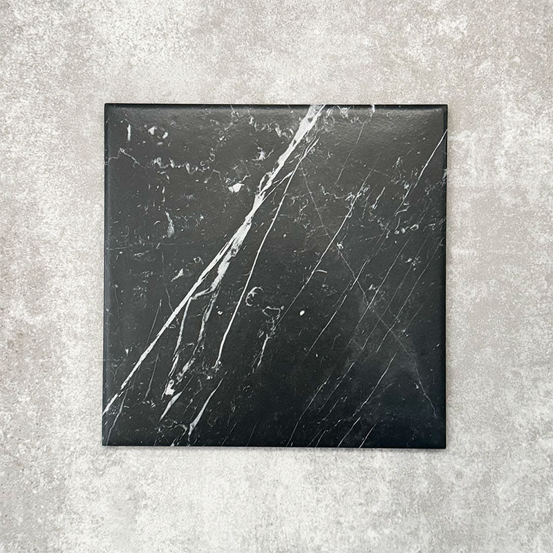Close-up of Florence Marquina Black 25x25cm marble-effect porcelain tile, featuring a deep black base with striking white veining and a smooth, realistic marble-look finish.