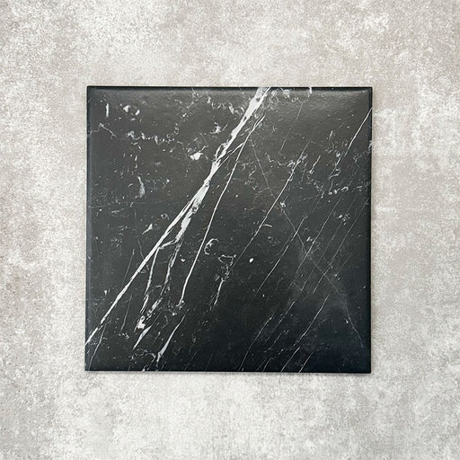 Close-up of Florence Marquina Black 25x25cm marble-effect porcelain tile, featuring a deep black base with striking white veining and a smooth, realistic marble-look finish.