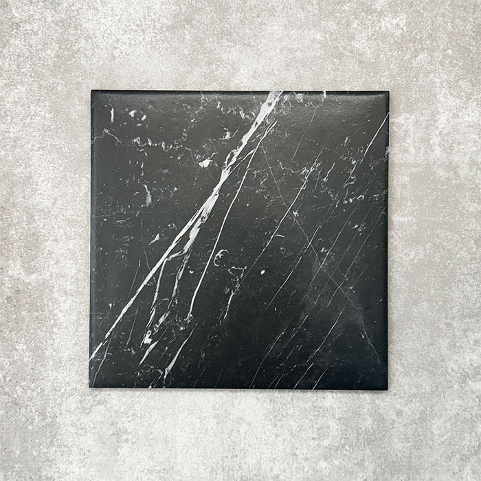 Close-up of Florence Marquina Black 25x25cm marble-effect porcelain tile, featuring a deep black base with striking white veining and a smooth, realistic marble-look finish.