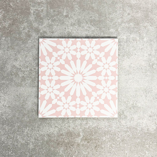 Fez Rose Pink Moroccan-style porcelain tile in a 20 × 20cm square format, shown as a single tile. The design features a soft blush pink background with a crisp white geometric starburst pattern inspired by traditional Moroccan motifs. Delicate yet detailed, the symmetrical pattern creates a light, elegant look that feels both decorative and refined—ideal for adding subtle colour and pattern to floors or walls without overwhelming a space.