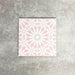 Fez Rose Pink Moroccan-style porcelain tile in a 20 × 20cm square format, shown as a single tile. The design features a soft blush pink background with a crisp white geometric starburst pattern inspired by traditional Moroccan motifs. Delicate yet detailed, the symmetrical pattern creates a light, elegant look that feels both decorative and refined—ideal for adding subtle colour and pattern to floors or walls without overwhelming a space.