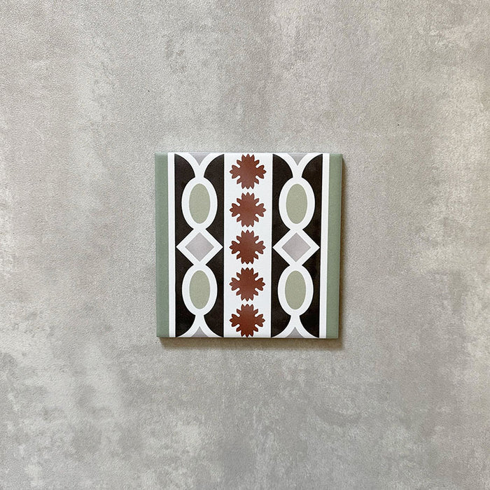 Single Imperial Victorian Green Mini Border Tile, 15x15cm porcelain tile featuring a classic Victorian-inspired border pattern in green, black, white, and terracotta tones, photographed on a neutral background.