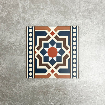 Single Balthazar Grand Side 20×20cm porcelain tile displayed against a neutral stone-effect background, featuring a bold Moroccan-inspired geometric border design in deep blue, warm brown, terracotta and cream tones, ideal for use as a decorative feature or edging tile.