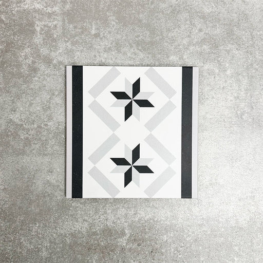 Single Canterbury Star Victorian-style porcelain border tile in a 20 × 20cm format, featuring a repeating star motif framed by contrasting black and grey stripes, shown on a neutral background to highlight its use as a decorative border for wall and floor layouts.