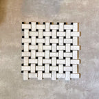 Single Fayrouz Black & White basketweave mosaic natural marble tile with a honed finish, featuring an intricate woven pattern with contrasting dark accents, displayed against a neutral textured background in a clean product setting.