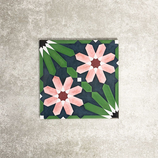 Single Fez Autumn 20x20cm Moroccan-style porcelain tile displayed against a textured grey background, highlighting the rich geometric floral design in deep green, navy blue and blush pink tones with an encaustic-inspired finish.