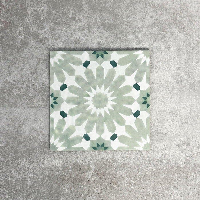 Single Fez Jade Green 20x20cm Moroccan-style porcelain tile displayed against a textured grey background, highlighting the soft green geometric star pattern and traditional encaustic-inspired design.