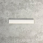 Close-up of Pimlico White 2.5 × 15cm ceramic pencil trim with a crackle glaze finish, showcasing soft white tones and a smooth rounded profile designed to neatly finish tiled wall edges.