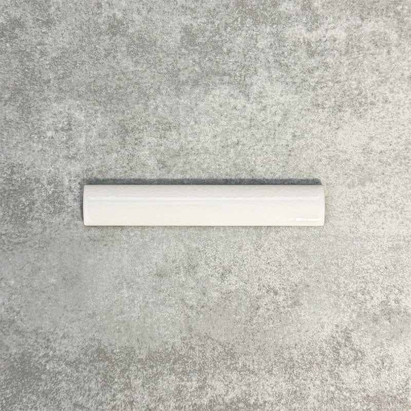 Close-up of Pimlico White 2.5 × 15cm ceramic pencil trim with a crackle glaze finish, showcasing soft white tones and a smooth rounded profile designed to neatly finish tiled wall edges.