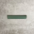 Pimlico Golders Green pencil trim tile measuring 2.5 × 15cm, finished with a crackle glaze and deep green tone, designed to neatly frame ceramic wall tiles and add a subtle decorative edge.