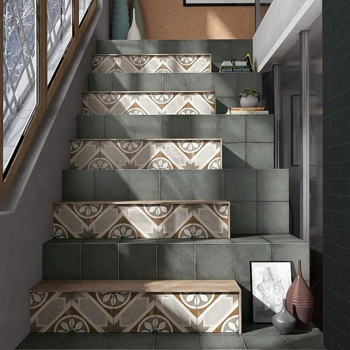 Victorian-style staircase featuring Viscount Heythrop 20×20cm porcelain wall and floor tiles used on stair risers, showcasing a repeating geometric floral pattern in soft grey, warm beige and muted blue tones, paired with solid green tiles on the treads for a characterful, design-led finish.