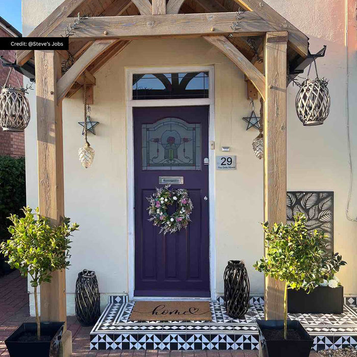 Exterior entrance featuring Richmond Decor Black Manor 20x20cm Victorian style floor tiles, showcasing a bold geometric pattern, used on steps and porch flooring, paired with a timber canopy, potted greenery and a classic front door.