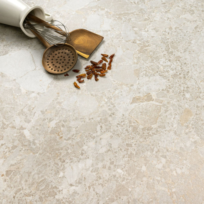 Kitchen surface featuring Essentials Terrazzo Stone Avorio 60x120cm terrazzo effect porcelain tiles, styled with brass utensils, a ceramic container, and warm neutral tones highlighting the soft stone-inspired variation.